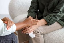 mental support to hold hands, handshake. An African-American female psychologist holds an appointment with a patient in the office. mental health and moral support. a female patient with mental difficulties and a mental disorder. depression and insomnia
